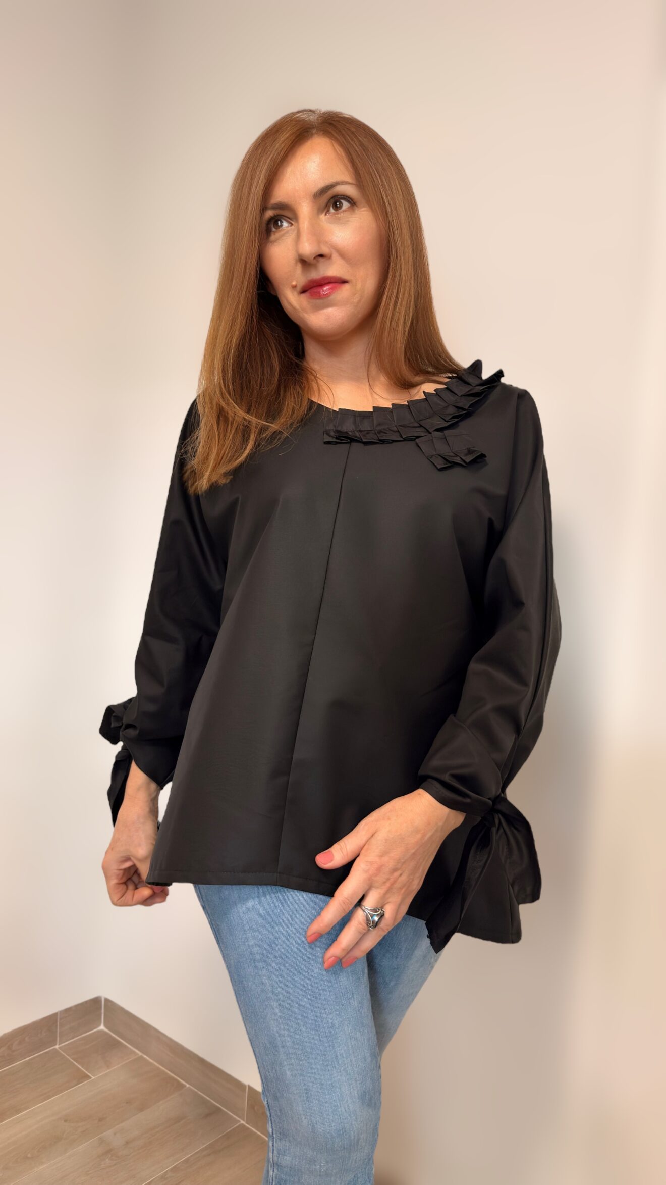 žena u elegantnoj crnoj bluzi s dekorativnim izrezom