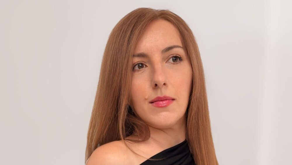 žena u elegantnoj crnoj off-shoulder haljini u minimalističkom okruženju