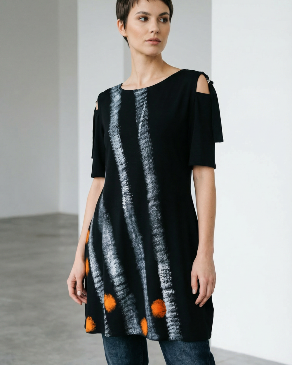 Model nosi crnu tuniku EVA s bijelim prugama i narančastim krugovima na traperice.