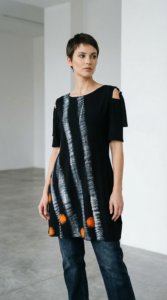 Model nosi crnu tuniku EVA s bijelim prugama i narančastim krugovima na traperice.