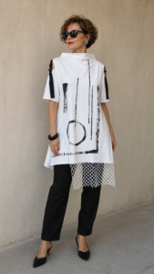 Žena nosi dizajnersku tuniku BLANKA crno-bijelog uzorka s mrežastim detaljem.