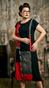 Model nosi REDY haljinu crne boje s crvenim detaljima, patchwork elementima i traper džepom iz kolekcije Kuky Design.