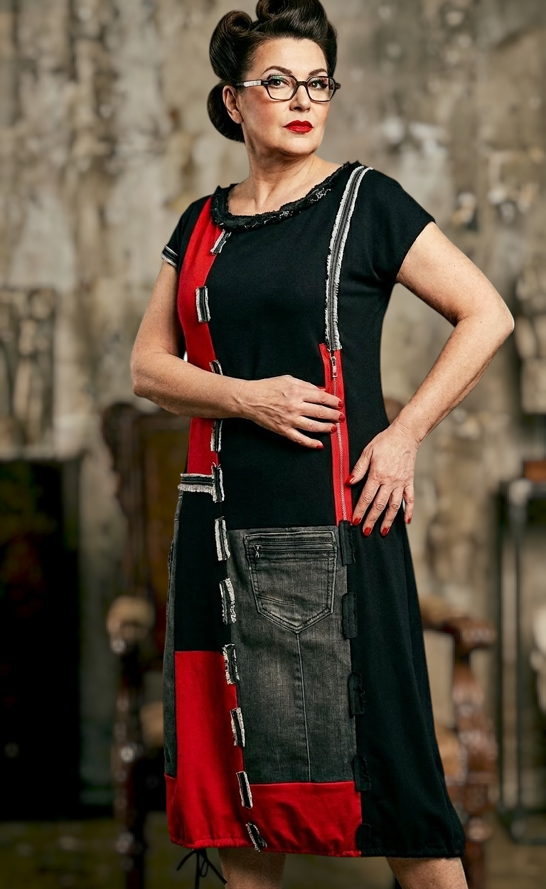 Model nosi REDY haljinu crne boje s crvenim detaljima, patchwork elementima i traper džepom iz kolekcije Kuky Design.